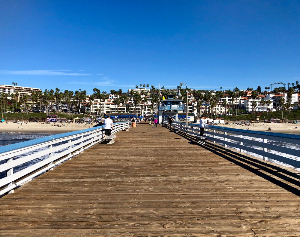 | people walking along san clemente pier on beautiful day