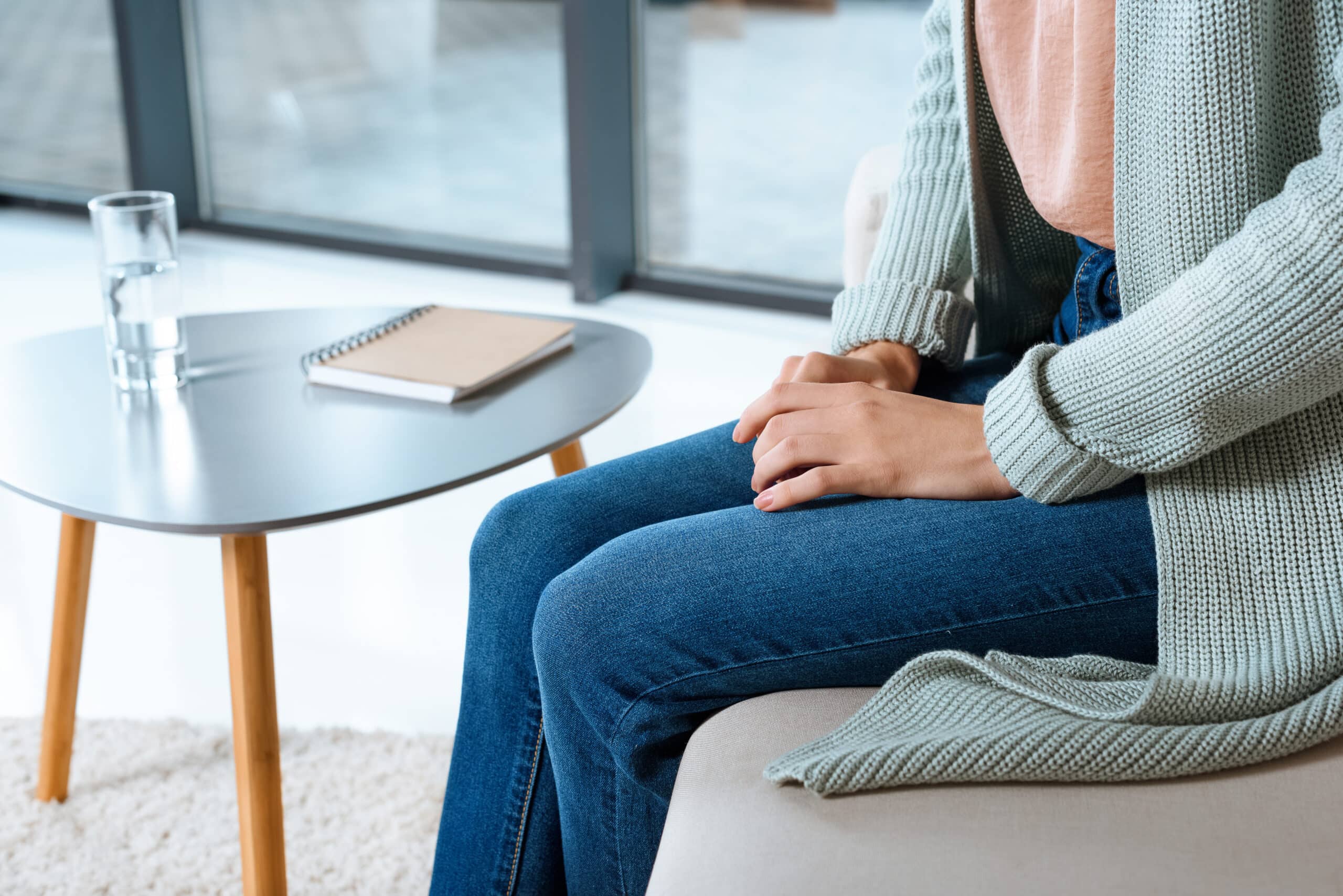 woman with her hands folded in her lap sitting on the couch