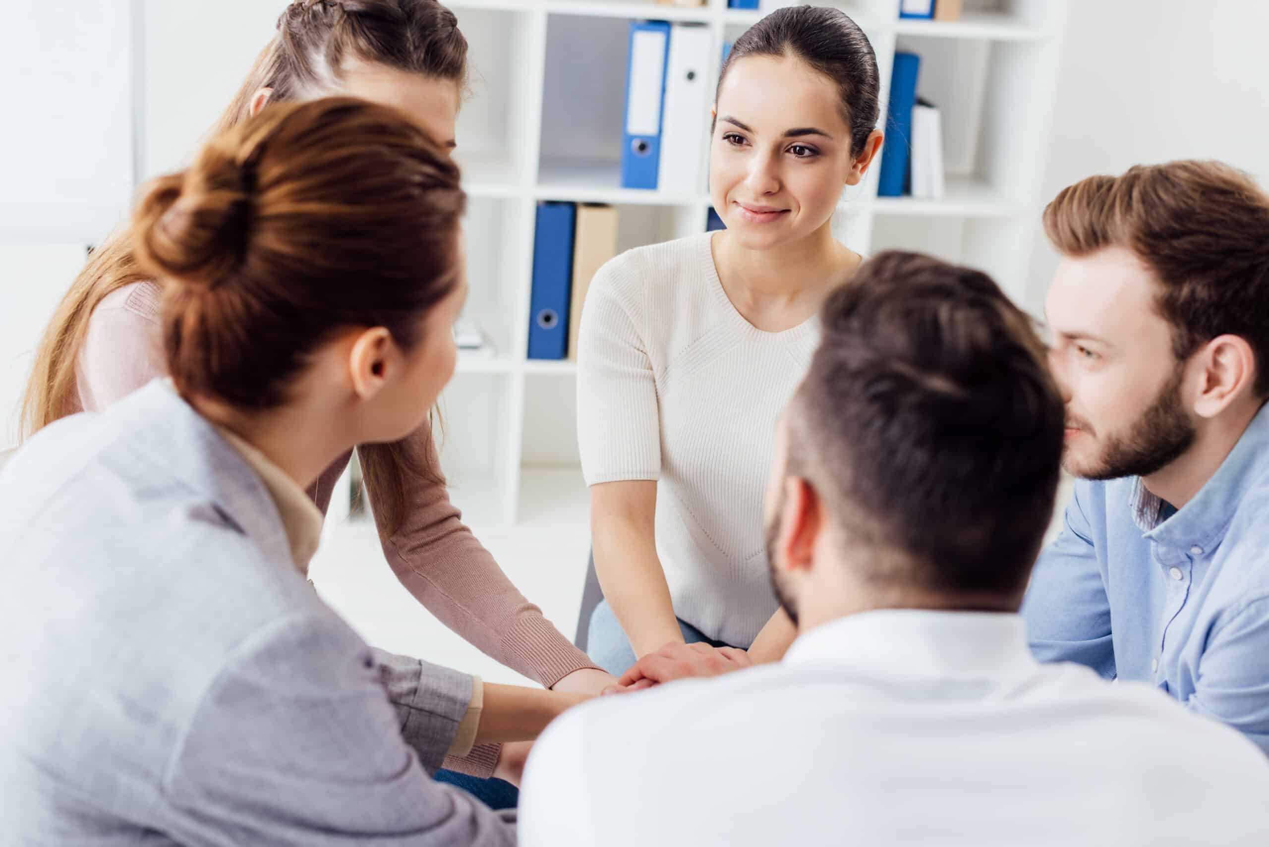 people sitting stacking hands during group therapy session