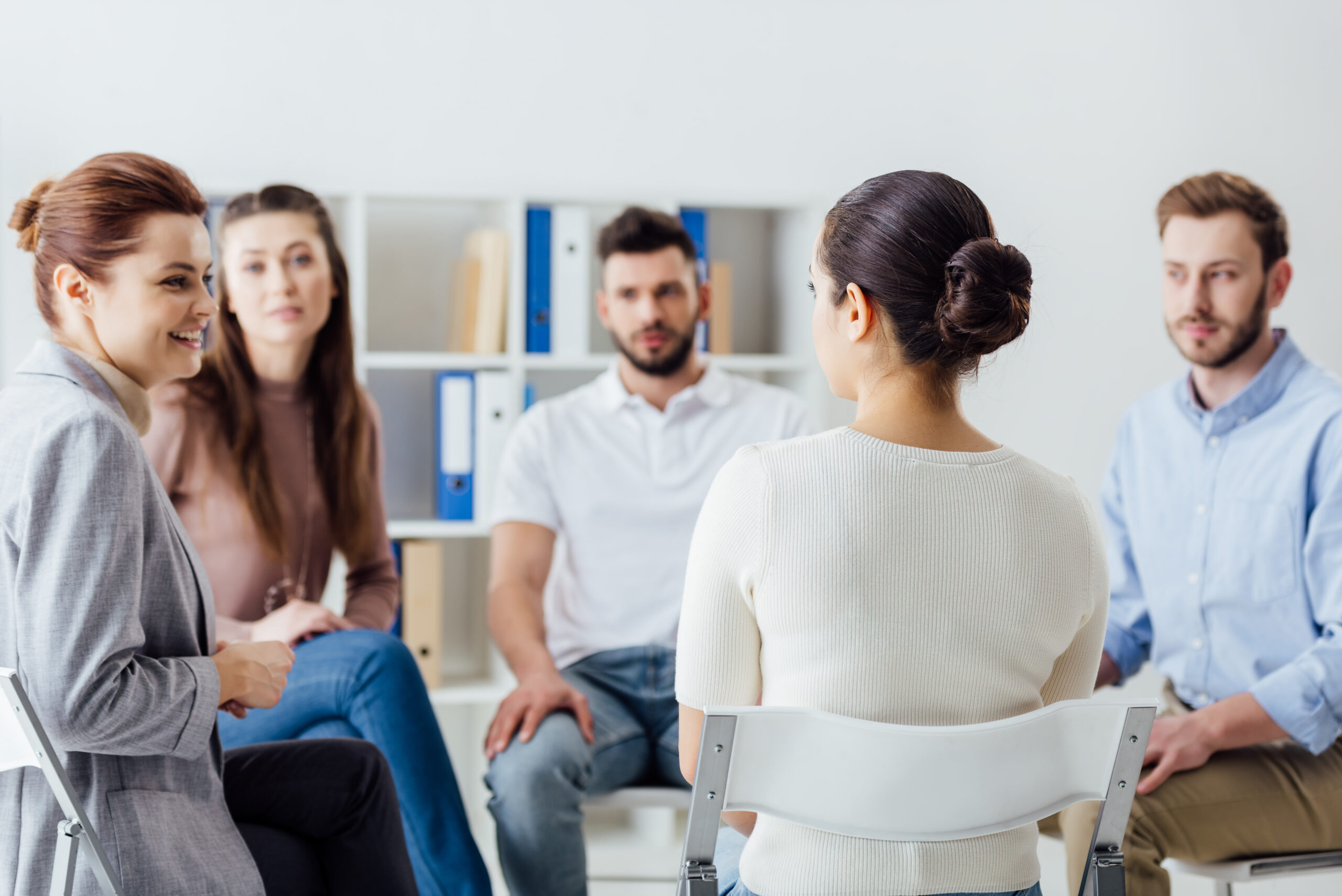 group of people sitting in circle on chairs during support group session