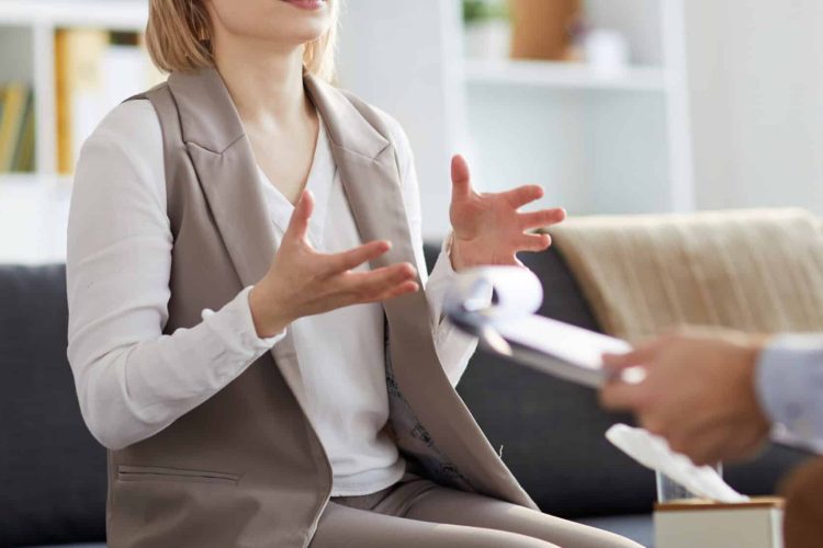 woman getting psychotherapy on a couch across from a therapist with a clipboard